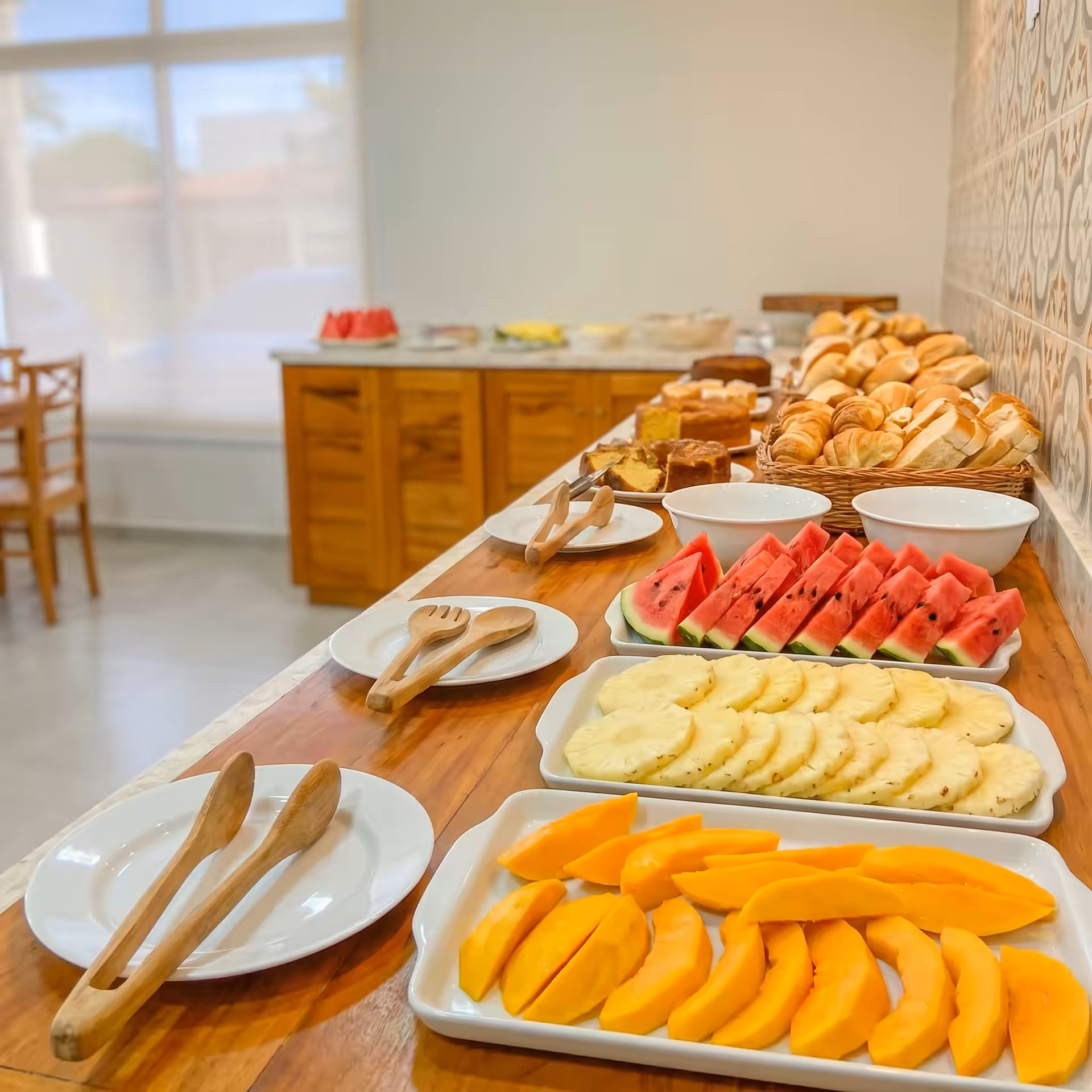 Buffet de café da manhã da Pousada Aquino Mar com frutas, pães e bolos em uma mesa ampla