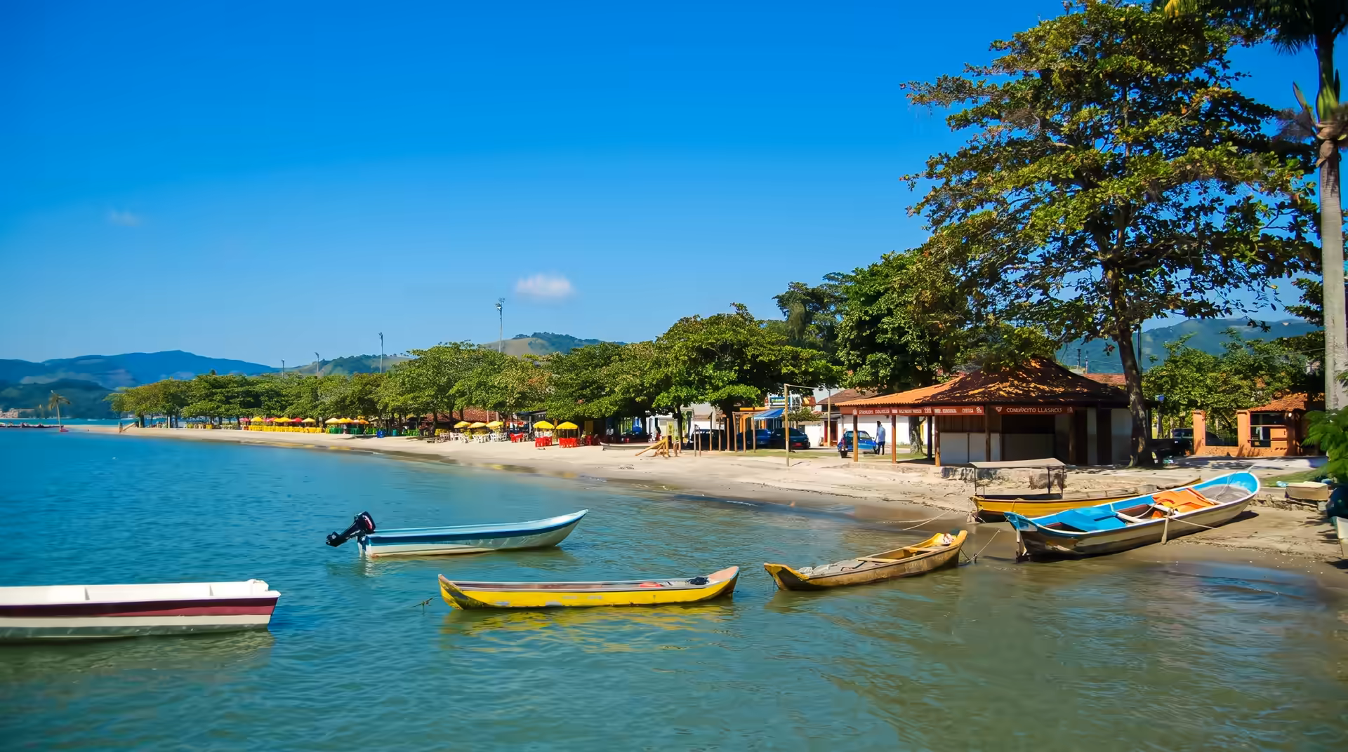 Praia do Pontal em Paraty com barcos e montanhas ao fundo